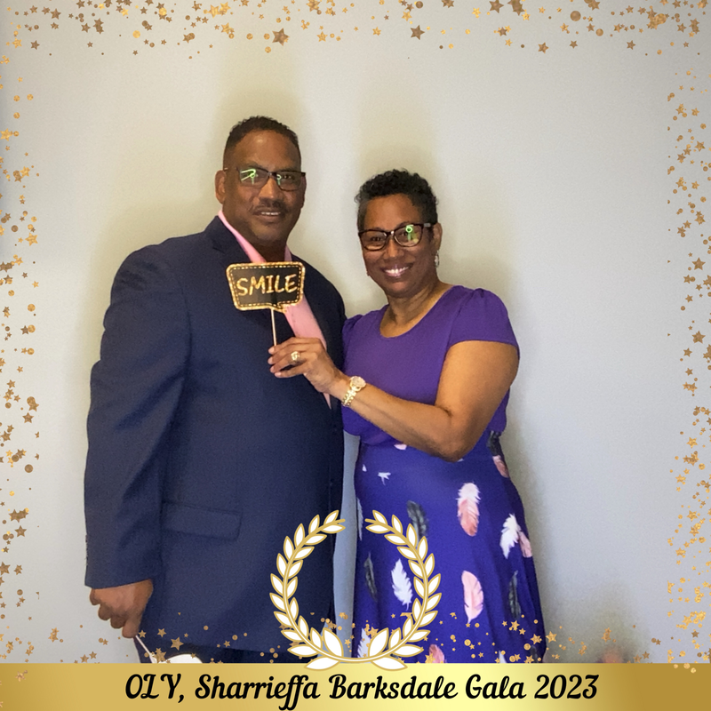 A couple posing with a SMILE sign in the gala 2023 photo booth
